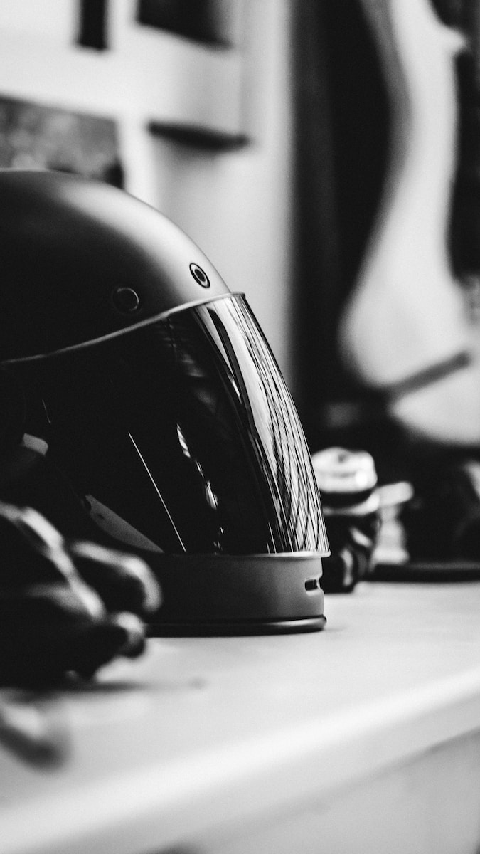 grayscale selective focus photography of full-face helmet on desk