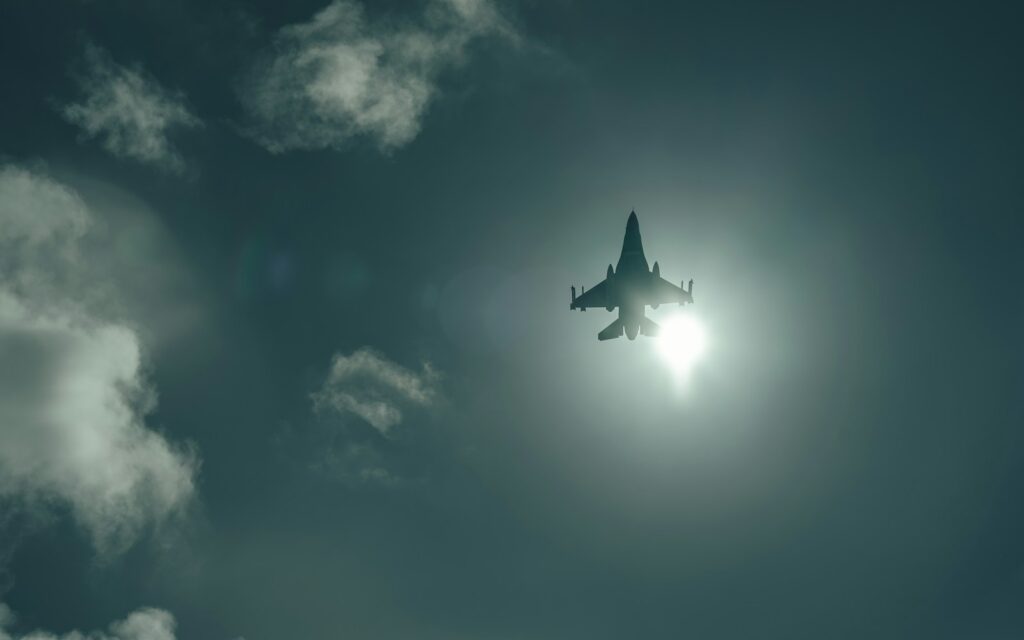 A jet flying through a cloudy blue sky